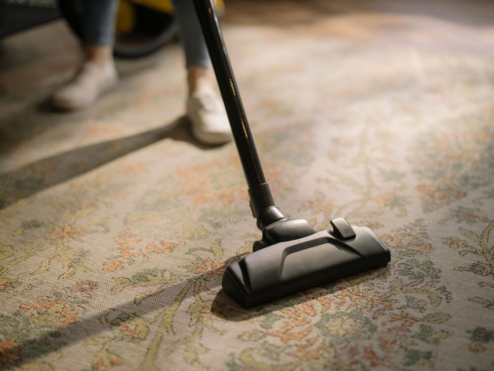 Close-up of a carpet cleaning wand on a patterned carpet