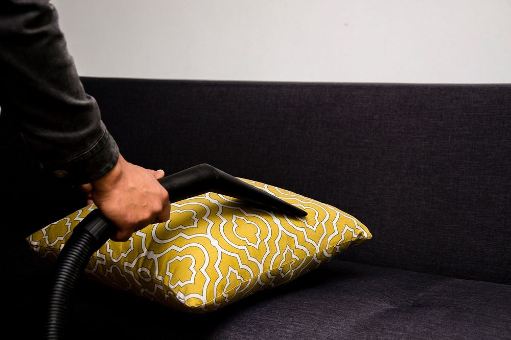 A cushion being cleaned with an upholstery tool