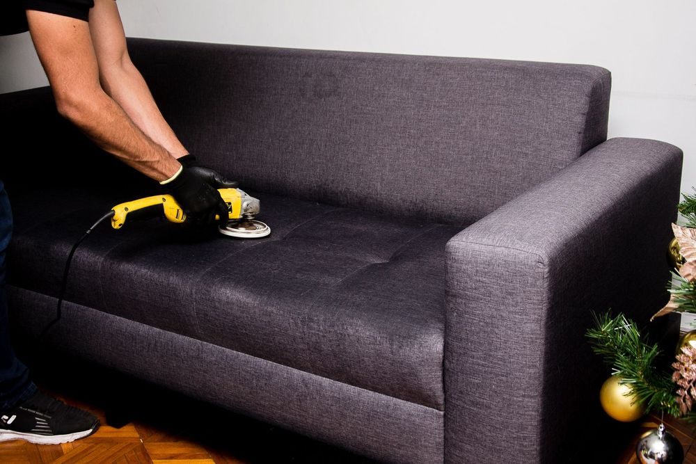 A deep clean being carried out on a dark fabric sofa